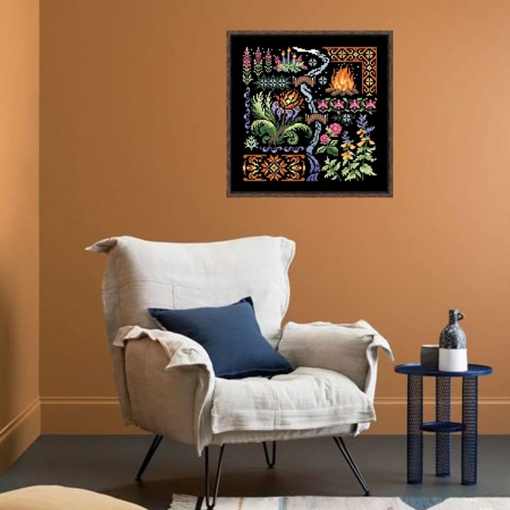 Framed Greenhouse cross stitch hanging above an armchair