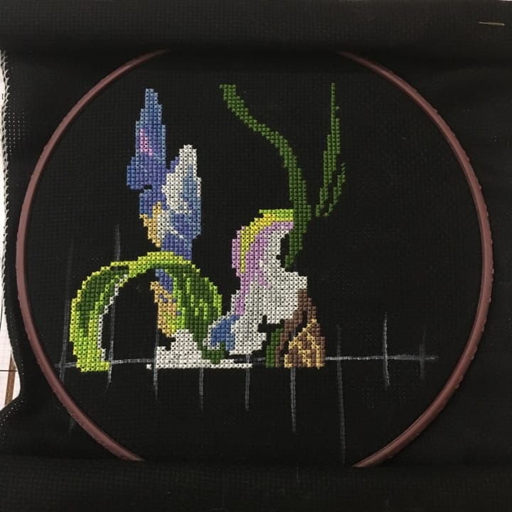 Iris cross stitch in progress on black Aida in a hoop