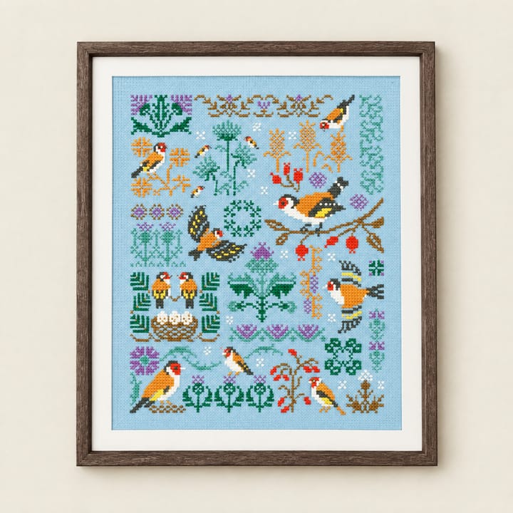 Goldfinch sampler cross stitch on sky blue Aida with thistles, rose hips and a nest, framed